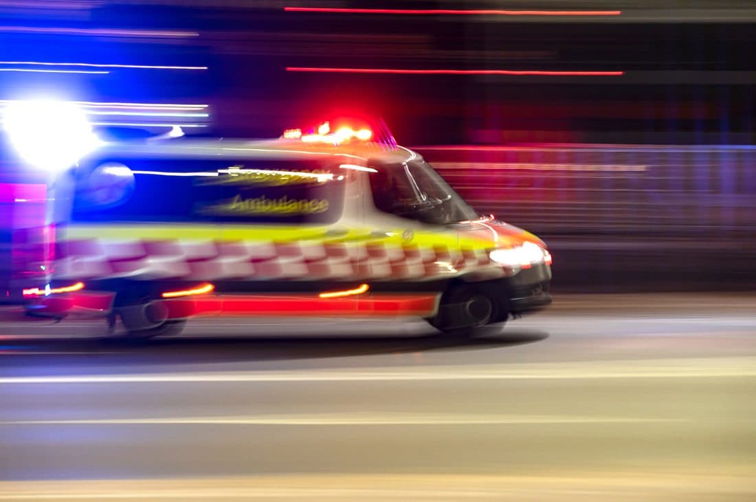 An emergency ambulance responding through city streets at night.